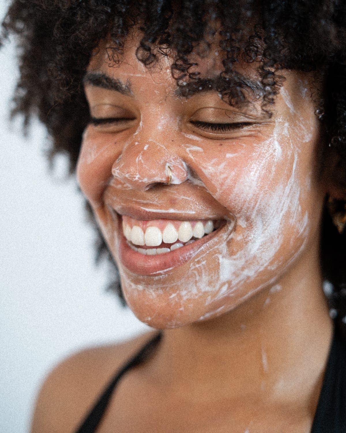 A woman smiling with Saene cleanser on her skin